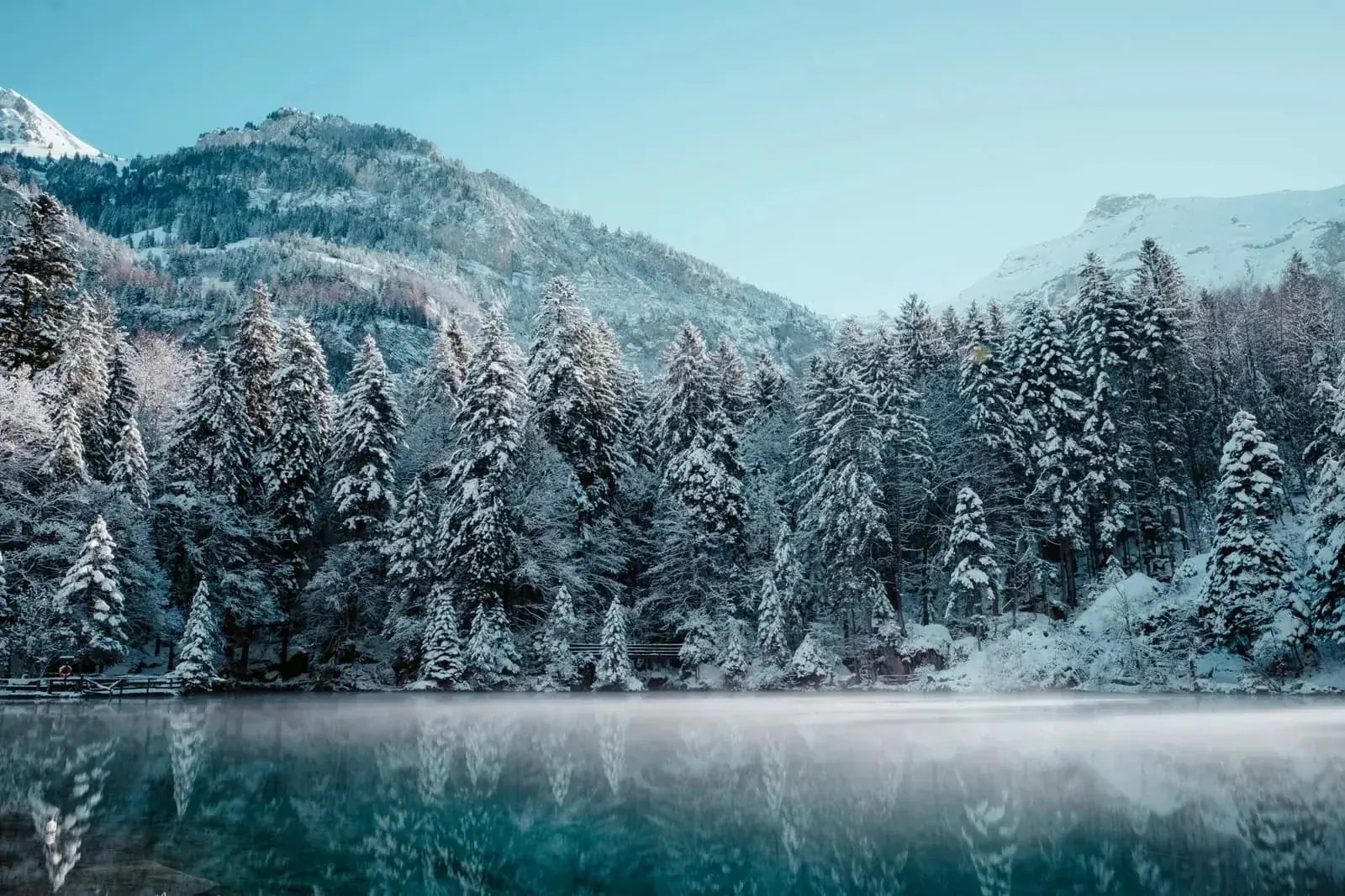 Tramway bleu historique sur des rails enneigés sous ciel d'hiver clair, Suisse